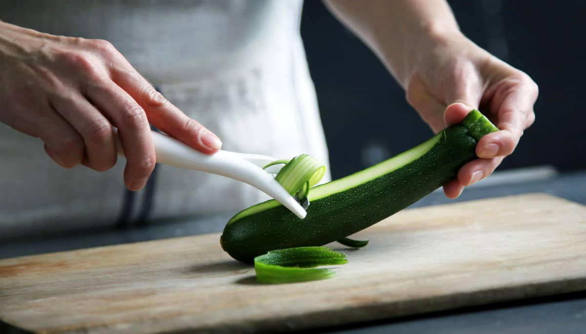 Eine Person beim Schälen einer Zucchini