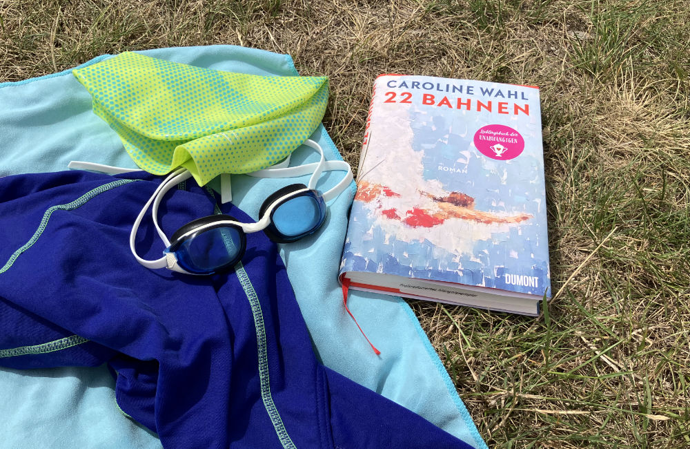 Buch "22 Bahnen" von Caroline Wahl und Schwimmsachen
